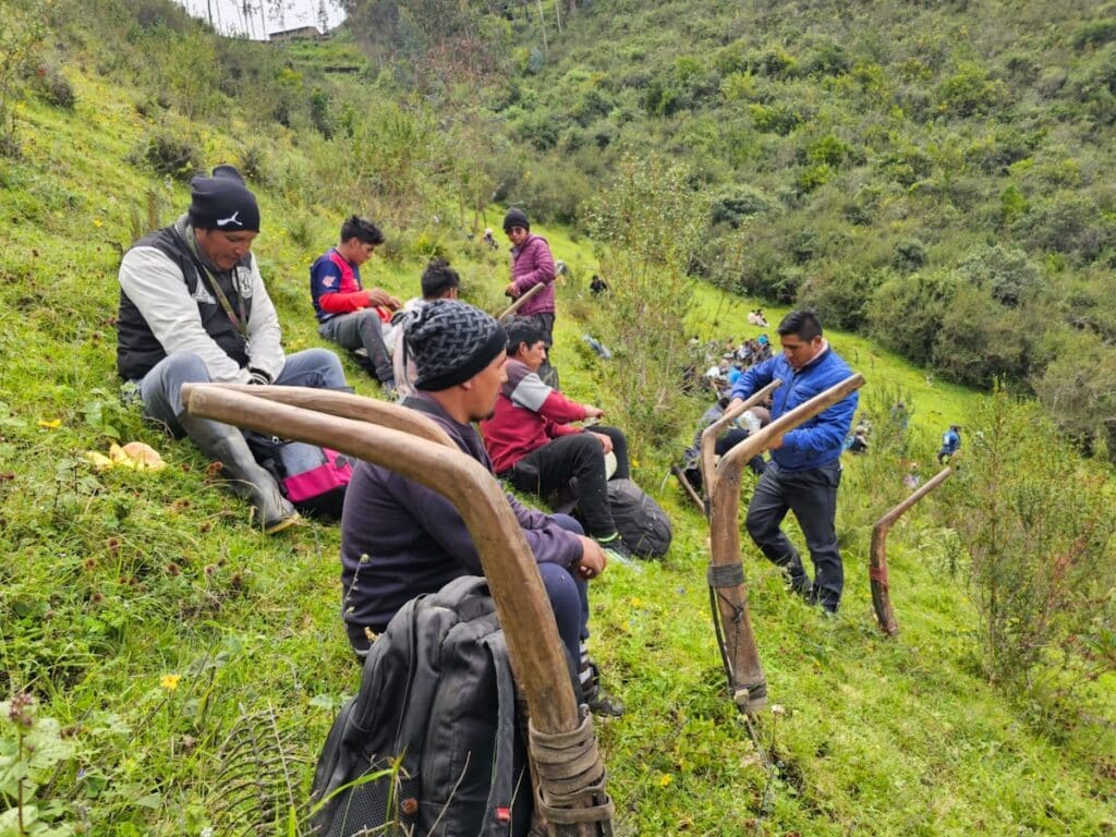 People sitting in a field next to plowing tools